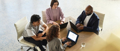 A group of people sitting around a table using laptops.