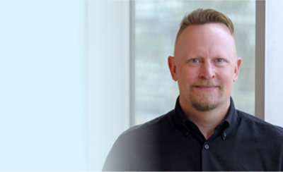A man wearing a black shirt is visible against a blue wall.
