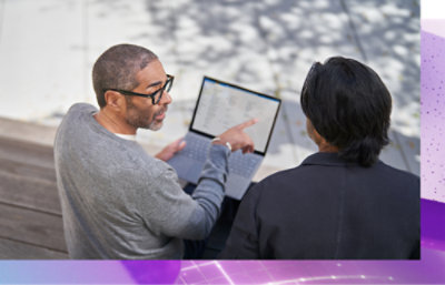 Una persona indica lo schermo di un computer e ne spiega il contenuto a un'altra persona.