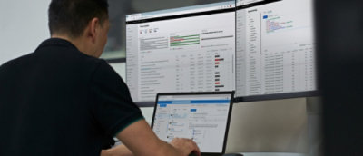 A person sitting at a desk using a laptop with a screen displaying graphs and charts.