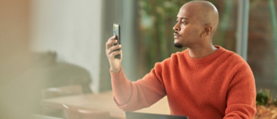 A person wearing an orange shirt holding a cell phone.