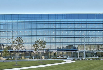 A large building with glass windows against a blue sky.