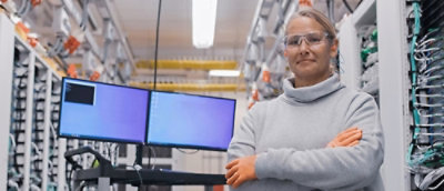 A person with their arms crossed in front of computer monitors