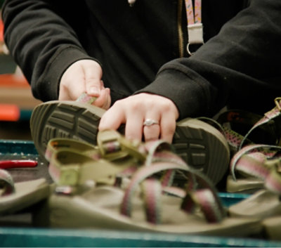 Een close-up van iemands handen die een schoenveter strikken.