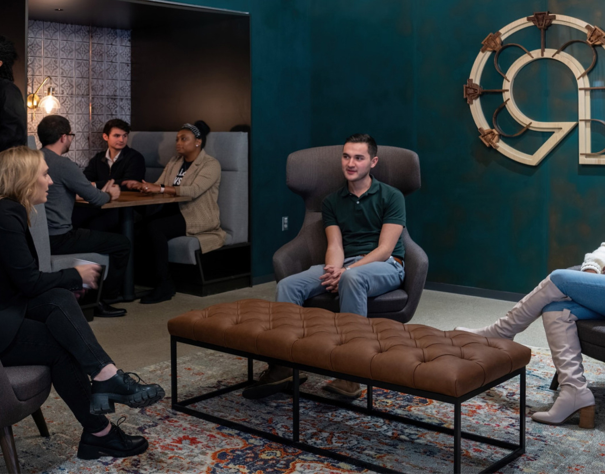 Un grupo de personas en un salón de oficina moderno, algunos sentados y otros de pie, que participan en la conversación.