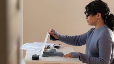 A person opening a laptop at their desk 