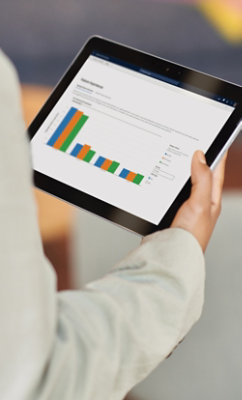 複数のカテゴリとさまざまな色付きバーを含む棒グラフを表示するタブレットを持っている人。