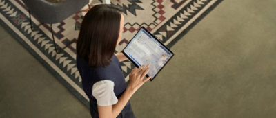 ด้านหลังของผู้หญิงที่ใช้แล็ปท็อปบนพรมที่มีลวดลาย