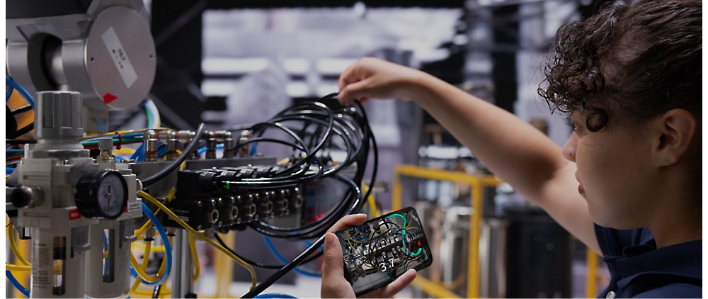 Un tecnico regola i cavi collegati a una struttura elettronica complessa in un ambiente di laboratorio.