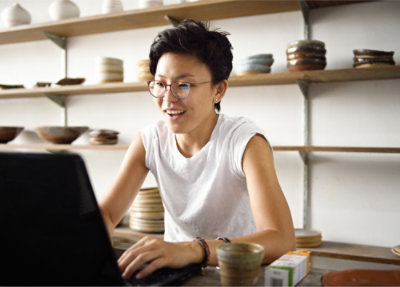 אישה יושבת ליד שולחן ומשתמשת במחשב נישא.