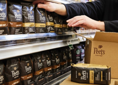 Osoba urovnávající balíčky kávy Peet's v obchodě