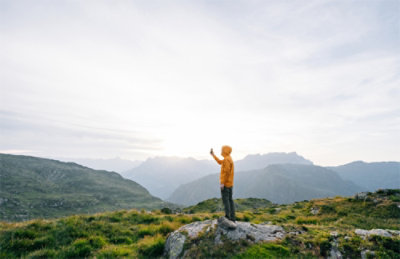 A person standing on a rock in front of mountains.
