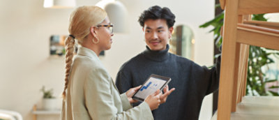 A man and woman looking at a tablet in a living room.