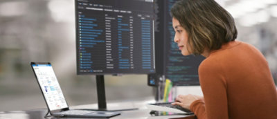 Woman analyzing data on computer screens in an office setting.