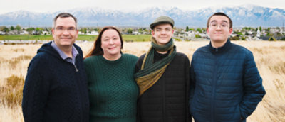 有四个人，三位男士，一位女士，站在户外的草地上 