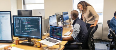 デスクのコンピューターで作業している人々。