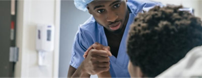 Doctor holding hand of boy in hospital bed