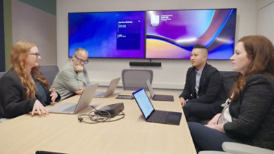A group of people sitting around a table with laptops.