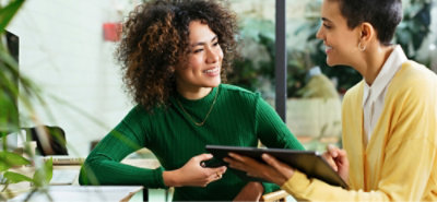 Two coworkers reviewing information together on a tablet in a bright office.