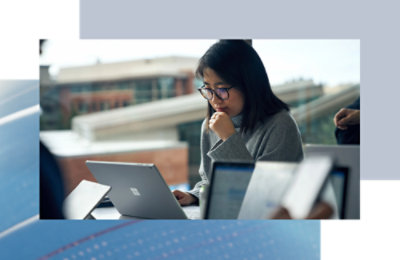 Person seated at a table, focused on working on a laptop in a shared workspace.