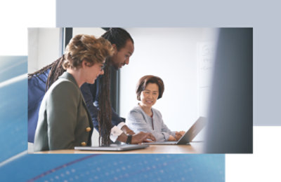Three coworkers gathered around a laptop, reviewing and discussing information together.