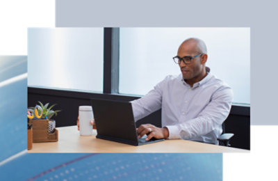 Person seated at a desk, working on a laptop in a modern office setting.
