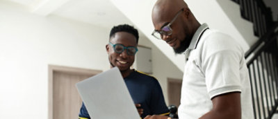 Two men sitting at a table looking at the laptop.