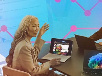 A laptop and two monitors are set up on a table, with text on one screen that reads eBooks.