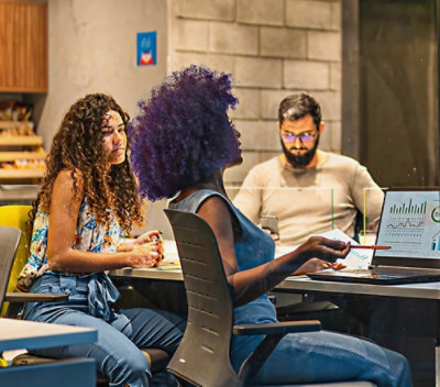A group of people sitting at a table looking at a laptop.