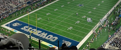 A football field with people in the stands and a visible sign displaying the numbers