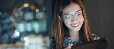 A person smiling while looking at her tab.