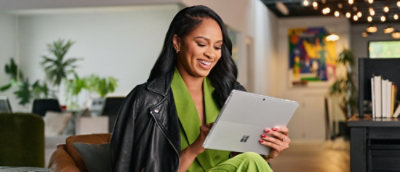 A person in a green and black jacket holding a tablet.