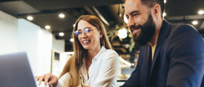 Two people smiling while looking at a laptop.