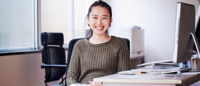 A woman sitting at a desk smiling.