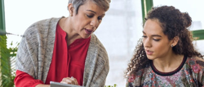A woman showing her tablet screen to another women.