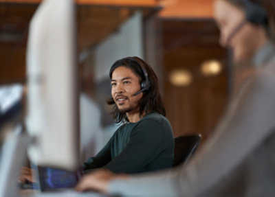 Person wearing headset working on computer in office environment for customer support or CRM system tasks