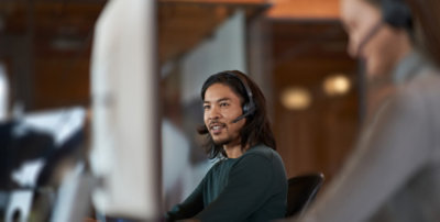 Person wearing headset working on computer in office environment for customer support or CRM system tasks