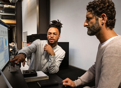 Two people looking at a laptop and having a discussion.