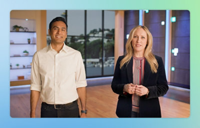 Two working professionals standing in a room and smiling.