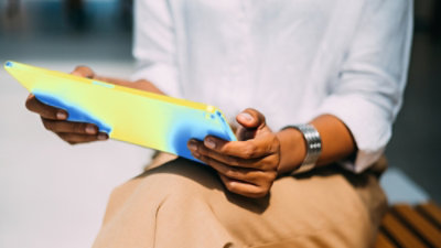 Person holding a tablet with a colorful data visualization overlay.