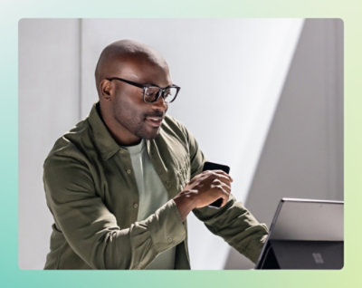 A man wearing glasses is looking at his phone.