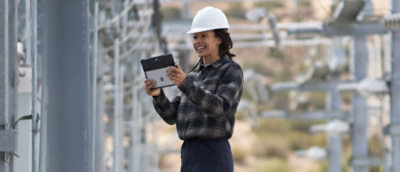 A person wearing a hard hat and holding a tablet.