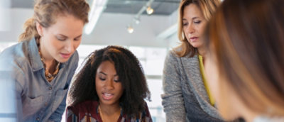Four women looking at something together.