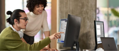 A men pointing at a desktop and explaining to co employee.