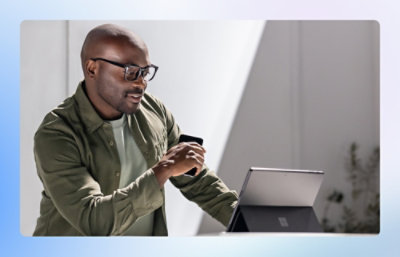 Person using a laptop and holding a smartphone in a workspace.