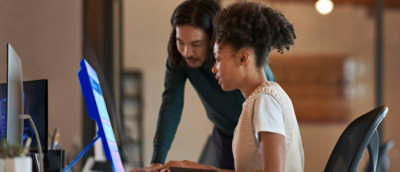 Two coworkers collaborating at a desktop computer in an office. Provide your feedback on BizChat