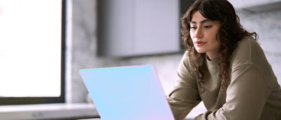 Person working on a laptop near a window in a modern workspace.