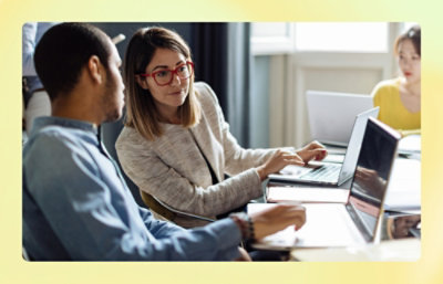 A women showing something on screen to a man in office.