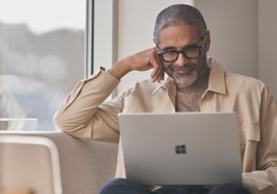A man sitting in sofa and using laptop.