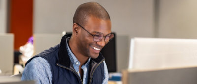 A man wearing glasses looking at a computer.